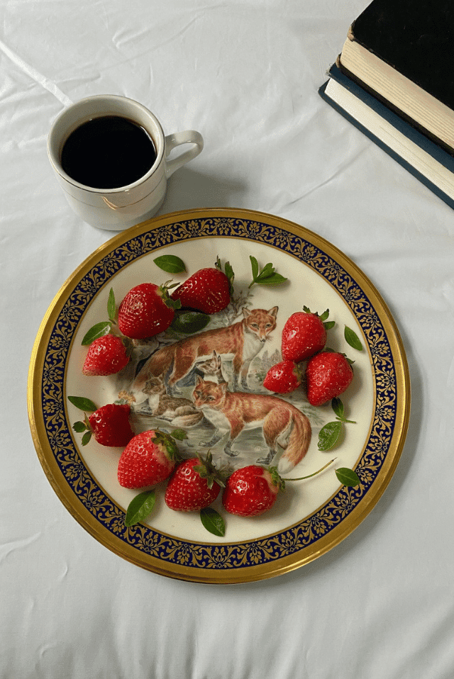 a cup of vegan coffee next to a plate of vegan strawberries